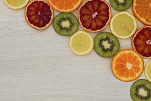Grapefruit, kiwi, lemon and orange wheels laid flat on a light wood grain background