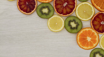 Grapefruit, kiwi, lemon and orange wheels laid flat on a light wood grain background